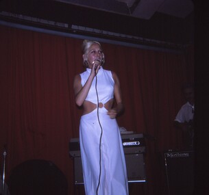 Female entertainer in white dress performing with microphone.