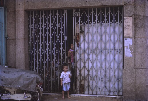 Grate doors covering entrance to building, with children at entry.