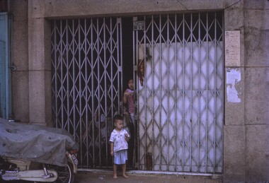 Grate doors covering entrance to building, with children at entry.
