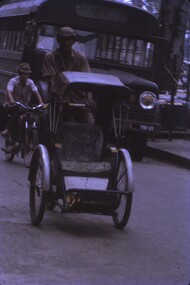 A three wheeled bike with covered seat at front and pedal powered by person on bike.