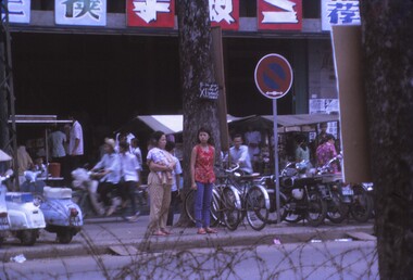 Bikes are parked on side of road and locals going about their busniess.