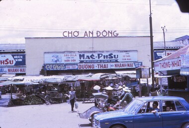 Shops and market stalls on a busy road.