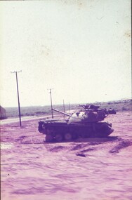 Military tank in dirt field.