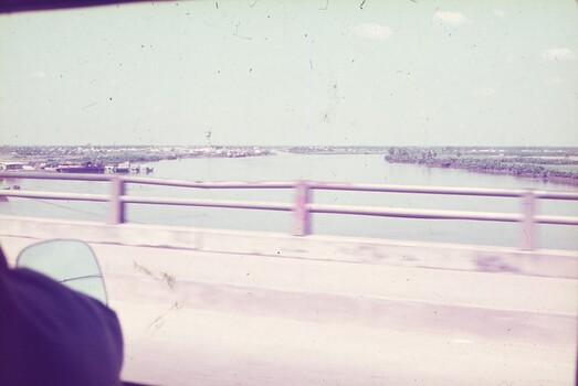A wide river taken from vehicle crossing bridge.