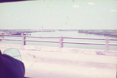 A wide river taken from vehicle crossing bridge.