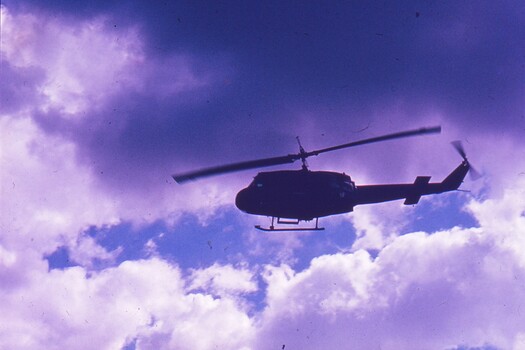 Helicopter in flight with clouds behind.