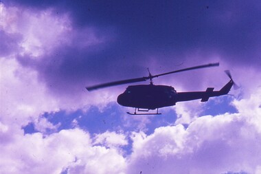 Helicopter in flight with clouds behind.