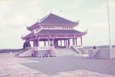 Open style building with Vietnamese architecture, columns and stairs leading up to it.