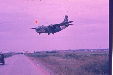 An aircraft coming into land, crossing over a road.