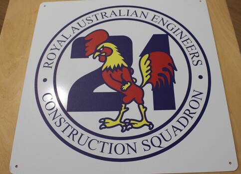 A white metal sign with the Royal Australian Engineers Construction squadron motif.