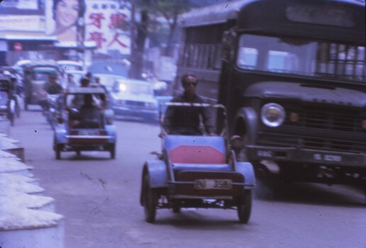Motorised rickshaws traveling on a road with buses, bikes and vehicles.
