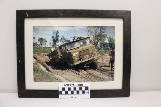 An army vehicle bogged in mud up to its back axle.