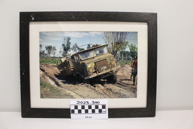 An army vehicle bogged in mud up to its back axle.