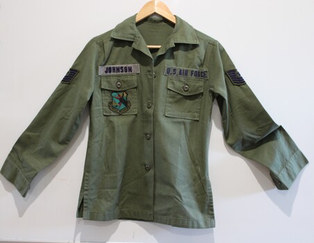 U.S long sleeve green shirt with pockets on each chest  and insignia on and above the pockets.