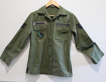 U.S long sleeve green shirt with pockets on each chest  and insignia on and above the pockets.