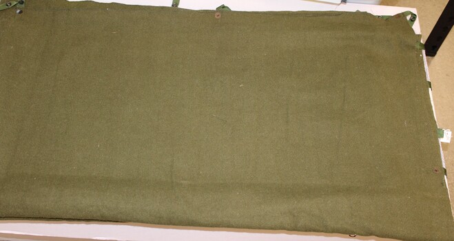 Khaki army issue woollen blanket with press studs and tabs to join the blanket it half.
