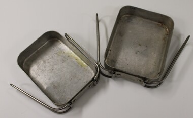 Two metal mess tins with folding handles. One fits inside the other.