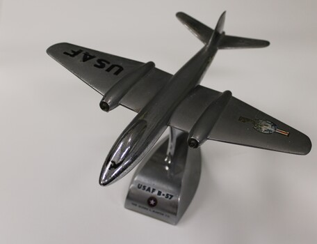 A solid metal model of a USAF B57 on a metal stand.