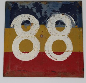 A metal sign with blue, yellow and red paint and the number 88 in white in the centre.