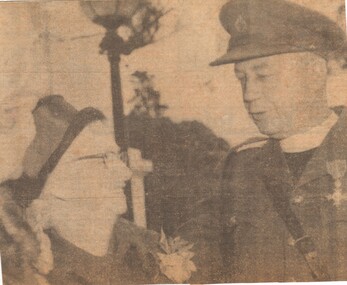 A Newspaper Clipping of Father Harry Brennan Talking To A Well Dressed Lady