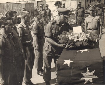 A Black and White Photograph of an Australian Officer Placing a Wreath on a Coffin.