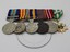 Six medals attached to coloured ribbons.