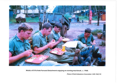 Medics sitting on a bench eating an evening meal. 1968
