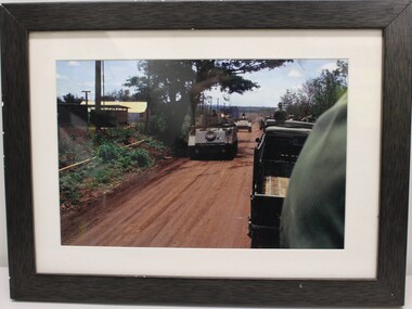 Convoy of Military Army Vehicles Moving Along a Red Dirt Road
