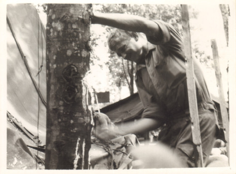 A Black and White Photograph of a Soldier Leaning Against a Tree