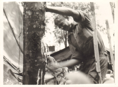 A Black and White Photograph of a Soldier Leaning Against a Tree