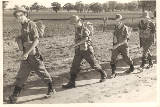 A Black and White Photograph of Four Soldiers Marching