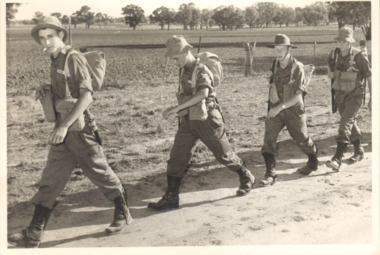 A Black and White Photograph of Four Soldiers Marching