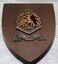 Small wooden plaque with metal badge afixed.