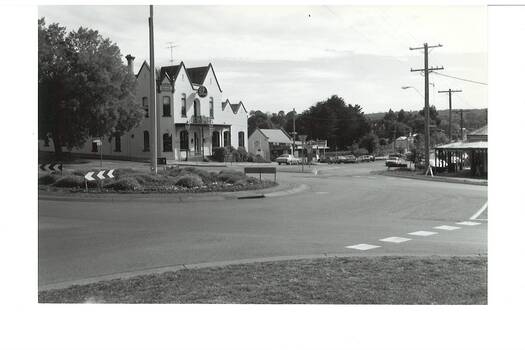 Streetscape showing roundabout intersection, Crown Hotel centre background, bottle shop next door, and corner shop visible on right.