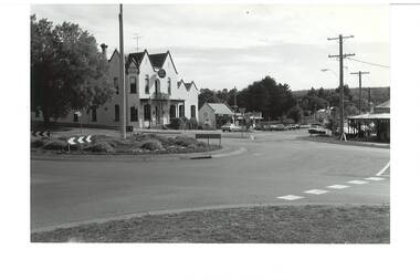 Streetscape showing roundabout intersection, Crown Hotel centre background, bottle shop next door, and corner shop visible on right.