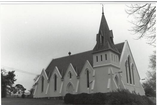Uniting Church looking uphill from eastern side, white rendered, showing four gables and five buttresses, belltower and steeple, slate roof.  Formerly Presbyterian Church