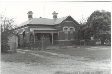 Former Police Station, brick building, rendered cornice and window capping, two chimneys , L-fronted with half verandah, tin roof, tree on right.