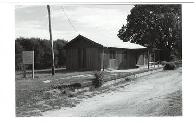 Remains Buninyong Railway Station platform, (built 1889) sign on left, power pole and Tennis Club shed, elm tree behind right..