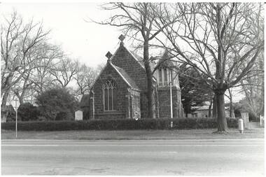 Gothic style, bluestone church, gabled entrance, low square bell tower on right. 1857 School/hall visible behind through trees.