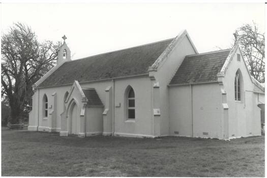 Church, Victorian Gothic Revival, gothic windows and door frames, whitewashed render, apse extendin on right, bell frame on peak of slate roof