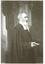 3/4 length portrait, side view of Reverend Thomas Hastie, wearing formal clerical attire, holding a religious book