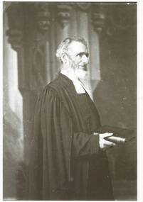 3/4 length portrait, side view of Reverend Thomas Hastie, wearing formal clerical attire, holding a religious book