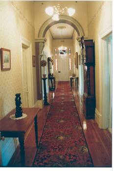 Interior view of hallway in "Mount Helen" showing decorative detail of the archway, wallpaper and leadlight of the front door.