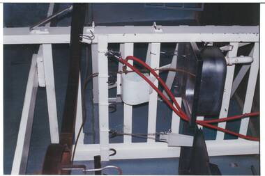 Close up of slaughterhouse washing area, white-painted steel railing, tubing leather belt