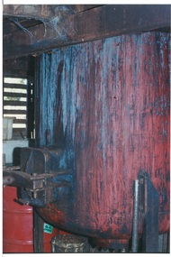 Metal vat, painted red with heavy stains running down sides, metal outlet with solid latch