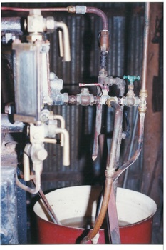 Pipes, taps and levers, feeding into red bucket
