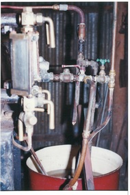 Pipes, taps and levers, feeding into red bucket