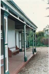 Wooden veranda, victorian era, decorative post and finials, gravel in front.