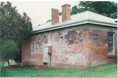 Rear old brick building, centre door, missing steps, tall sash window on side wall, twin chimneys, one missing finial, evidence of paint some areas.