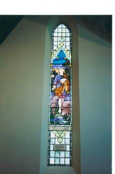 Tall, narrow gothic stained glass window, depicting Christ as Shepherd with flock.